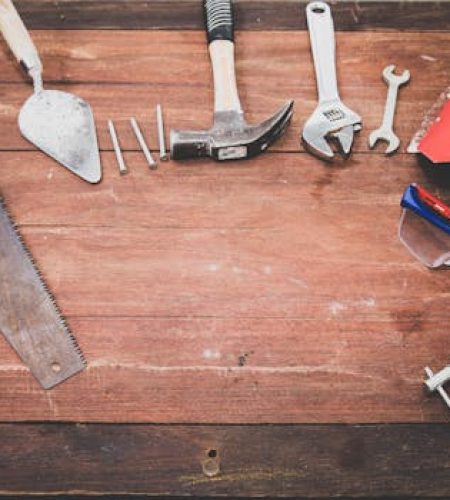 Flat lay of various workshop tools on a rustic wooden table, showcasing DIY essentials.